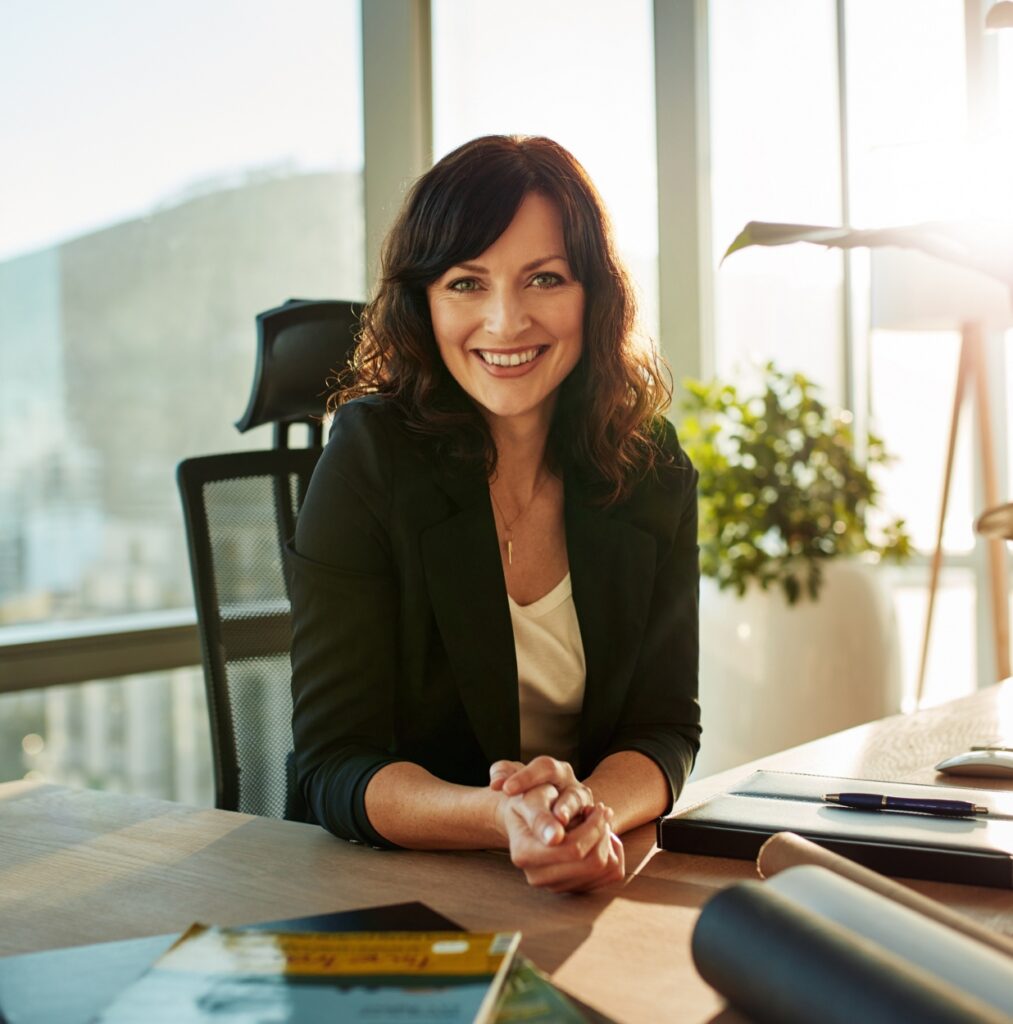 Queens Calls Woman CEO Smiling At Desk